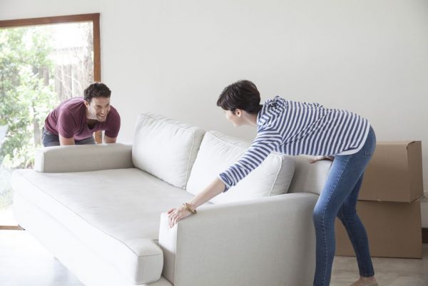 a couple moving their couch in their new home