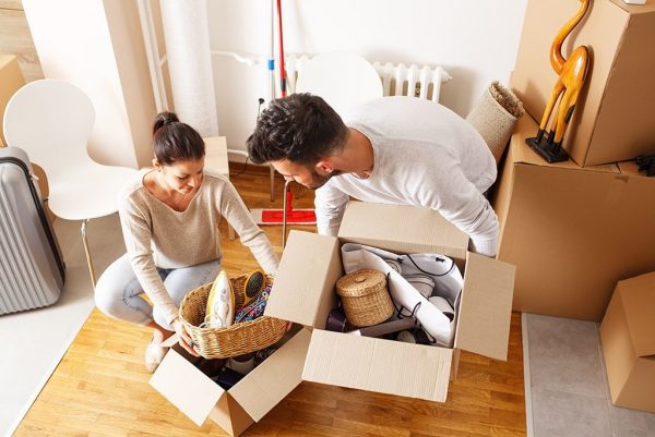 young couple unpacking cardboard boxes at new home