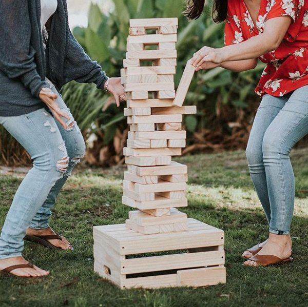 a man and a woman playing jenga at the backyard