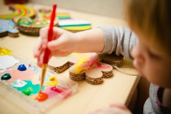 A kid painting on cardboard cutouts