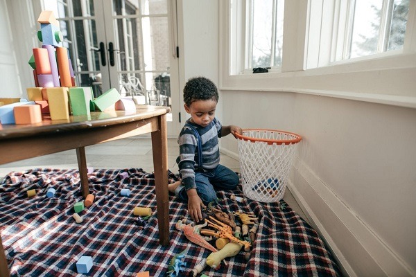 A toddler putting his toys in the basket