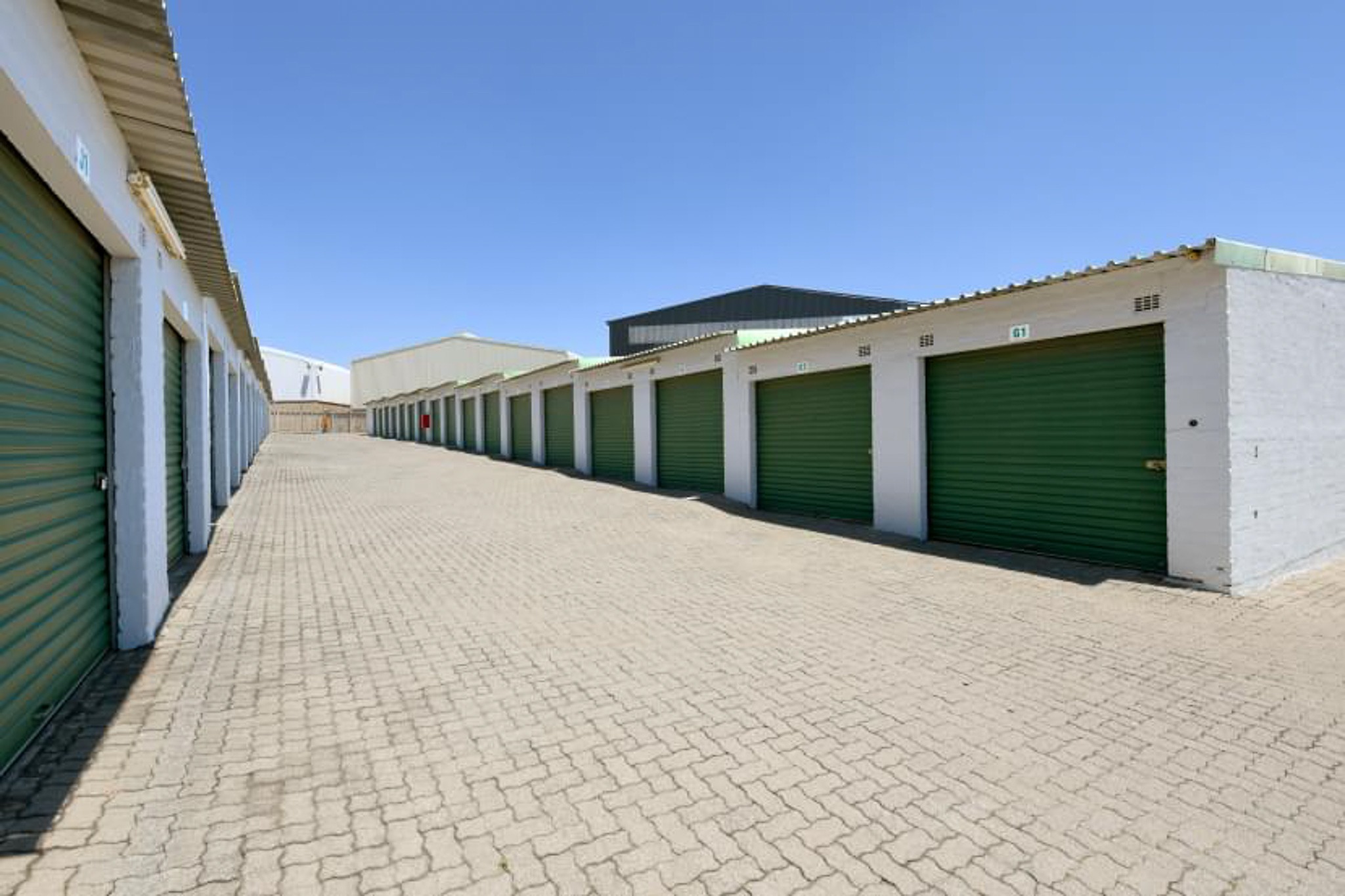 A row of storage units with white paint and green doors.