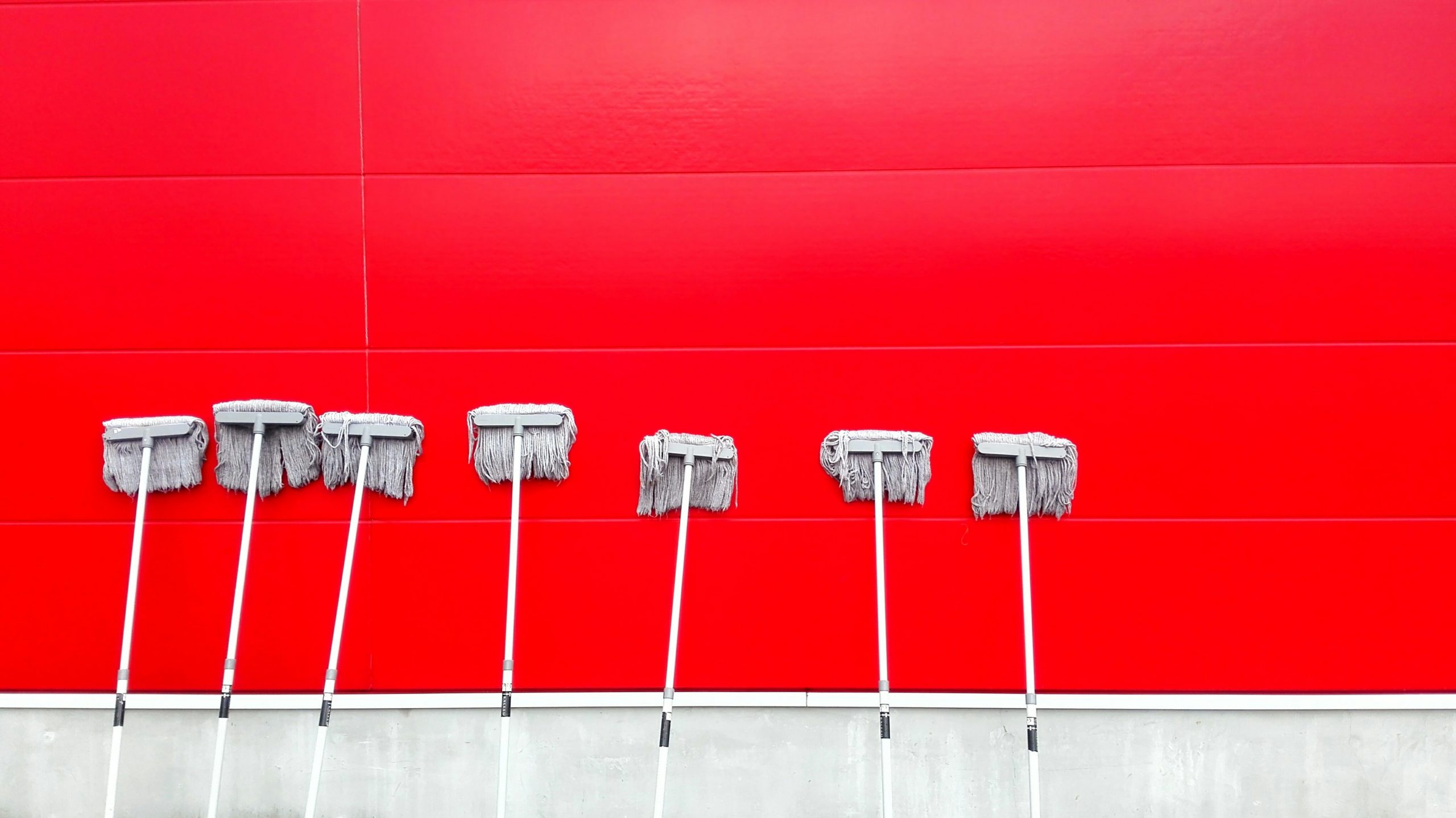 A red background wall with mops cleaning