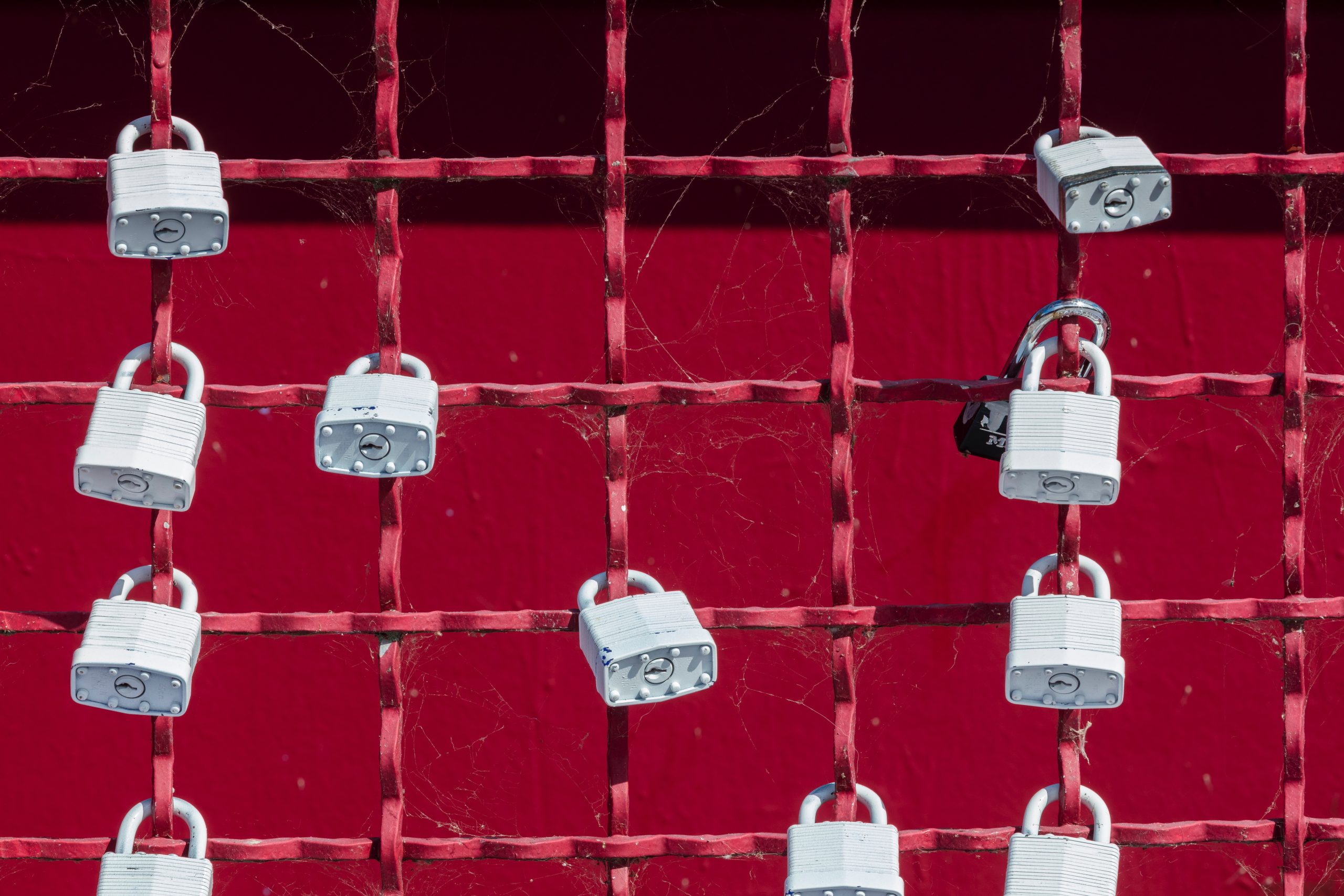 A gate with red paint and locks hanging off.