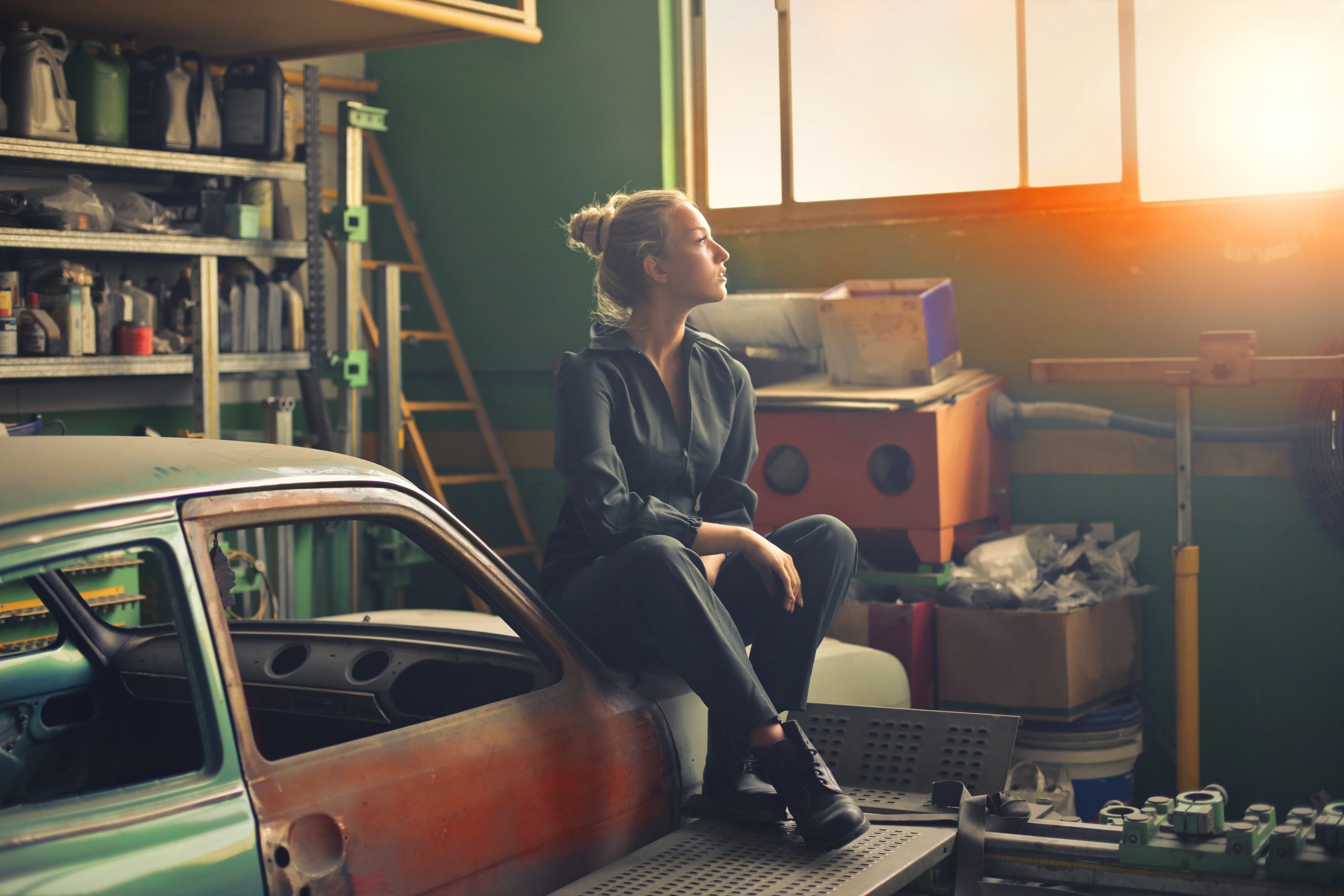 Woman sitting on top of a broken down car
