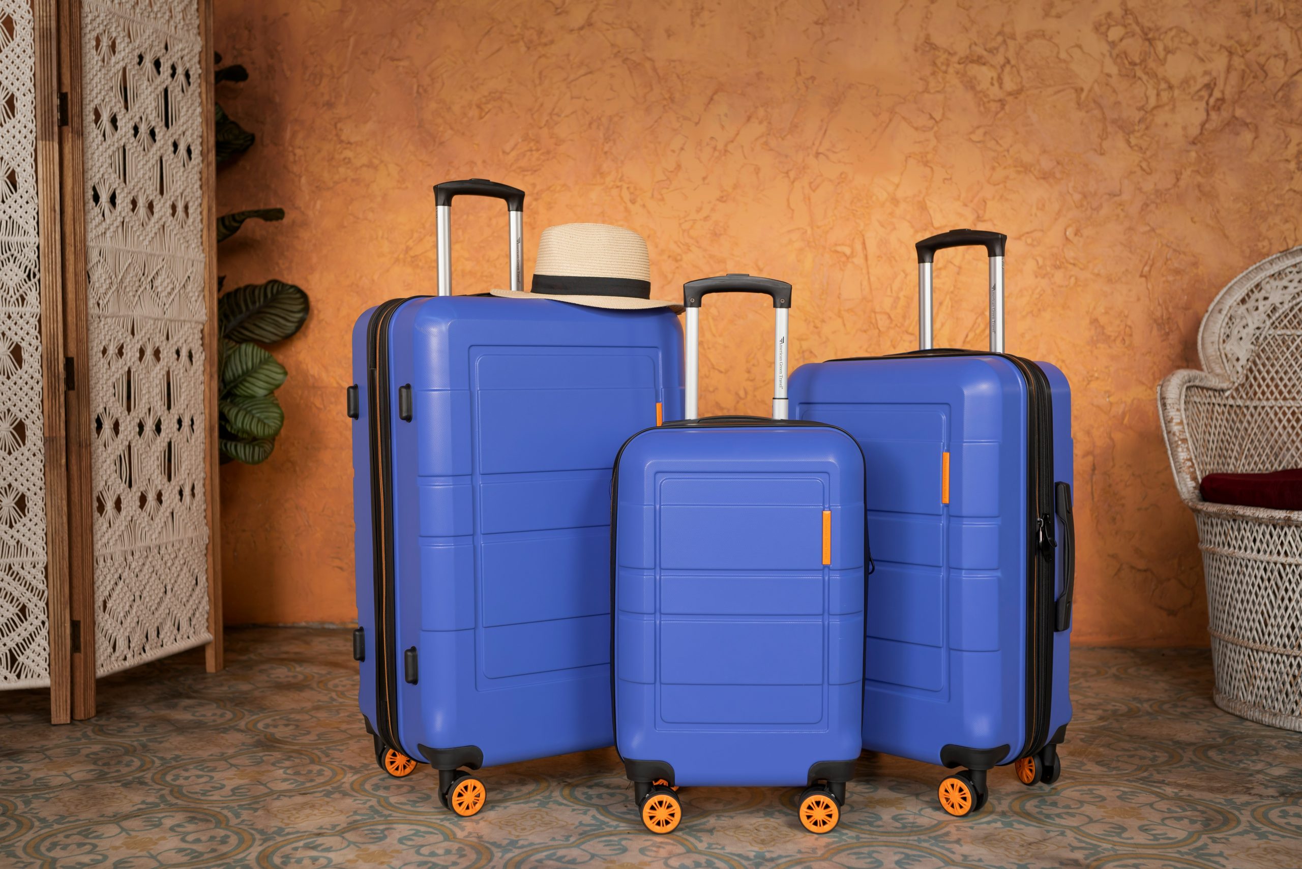 blue suitcase set with hat on top and orange background